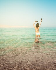 Wall Mural - Tourist woman stand in clear turquoise water in persian gulf Mirellas island sandy white beach. Oman coastline paradise. Musandam.