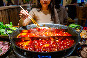 Female tourist eating original mala spicy hot pot in Chongqing, China