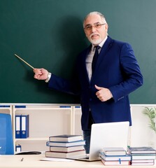 Wall Mural - Aged male teacher in front of chalkboard