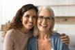 © fizkes - Cheerful beautiful adult daughter woman hugging happy blonde senior mom, holding shoulder with support, care, looking at camera with perfect toothy smile, laughing. Elderly mother headshot portrait