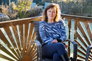 Woman sitting on a whicker chair, next to frosted spider webs.