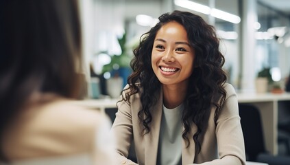 Wall Mural - A young Asian woman smiles during a conversation in a bright office