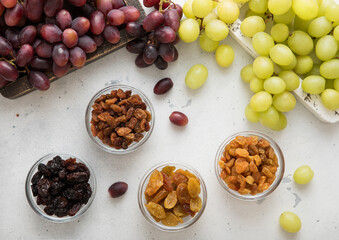 Wall Mural - Dried green and red dark raisins with ripe raw grapes on light background.Top view.