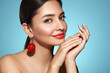 © Oleg Gekman - Portrait of beautiful young woman on blue background, red lipstick and festive makeup, Christmas toy earrings, shiny glowing skin, Winter holidays concept