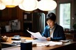 © Andrii Zastrozhnov - Focused Asian businesswoman working from home, reading paperwork and managing finance. Professional and serious demeanor.