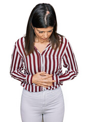 Wall Mural - Beautiful brunette woman wearing striped shirt with hand on stomach because indigestion, painful illness feeling unwell. ache concept.