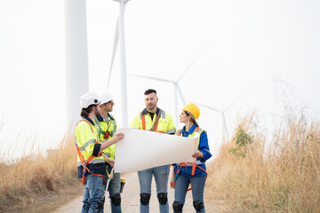 Group of male and female engineer working at wind turbines farm, discussing and inspecting quality wind turbines, planing maintenance of wind turbines at windmill field farm