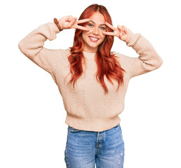 Poster - Young redhead woman wearing casual winter sweater doing peace symbol with fingers over face, smiling cheerful showing victory