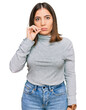 Young beautiful woman wearing casual turtleneck sweater mouth and lips shut as zip with fingers. secret and silent, taboo talking