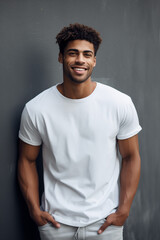 Wall Mural - Portrait of a young man standing a front of a gray wall with hands in pockets and smiling at the camera.