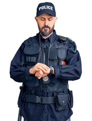 Wall Mural - Young handsome man wearing police uniform checking the time on wrist watch, relaxed and confident