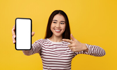 Excited young asian woman showing phone with mockup