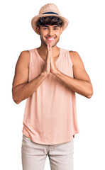 Canvas Print - Young hispanic man wearing summer hat praying with hands together asking for forgiveness smiling confident.