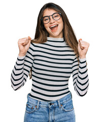 Poster - Young beautiful teen girl wearing casual clothes and glasses celebrating surprised and amazed for success with arms raised and open eyes. winner concept.