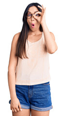 Sticker - Young beautiful caucasian woman wearing casual clothes and glasses doing ok gesture shocked with surprised face, eye looking through fingers. unbelieving expression.