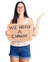 Sticker - Young beautiful caucasian woman holding we need a change banner celebrating victory with happy smile and winner expression with raised hands