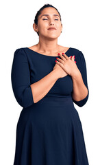 Poster - Young beautiful brunette woman wearing casual dress smiling with hands on chest with closed eyes and grateful gesture on face. health concept.