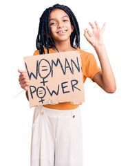 Wall Mural - Cute african american girl holding woman power banner doing ok sign with fingers, smiling friendly gesturing excellent symbol