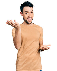 Canvas Print - Hispanic man with beard wearing casual t shirt smiling cheerful with open arms as friendly welcome, positive and confident greetings