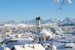 Blick auf das tief verschneite Nesselwang mit der Pfarrkirche St. Andreas, im Hintergrund die Alpen. Nesselwang ist ein Wintersportort, aber auch zu anderen Jahreszeiten sehr beliebt. Allgäu, Bayern.