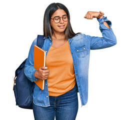 Canvas Print - Young latin girl wearing student backpack and holding books strong person showing arm muscle, confident and proud of power