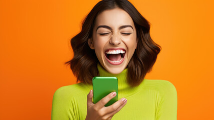 Wall Mural - Happy smiling young woman is using her smartphone against orange background