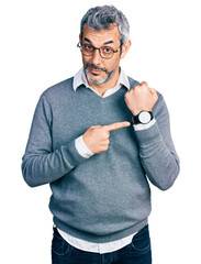 Canvas Print - Middle age hispanic with grey hair wearing glasses in hurry pointing to watch time, impatience, looking at the camera with relaxed expression