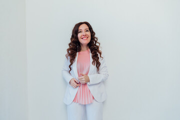 Beautiful brunette woman in white suit posing in bright studio