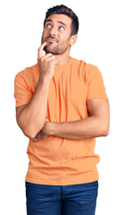 Wall Mural - Young hispanic man wearing casual clothes serious face thinking about question with hand on chin, thoughtful about confusing idea