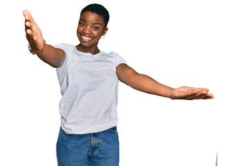 Poster - Young african american woman wearing casual white t shirt looking at the camera smiling with open arms for hug. cheerful expression embracing happiness.