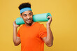 Young fitness trainer instructor sporty man sportsman wears orange t-shirt hold yoga mat look aside on area spend time in home gym isolated on plain yellow background. Workout sport fit abs concept.