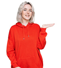 Sticker - Young blonde girl wearing casual clothes smiling cheerful presenting and pointing with palm of hand looking at the camera.