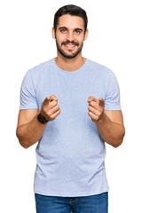 Wall Mural - Young hispanic man wearing casual clothes pointing fingers to camera with happy and funny face. good energy and vibes.