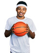 © Krakenimages.com - Young african american man holding basketball ball smiling with a happy and cool smile on face. showing teeth.