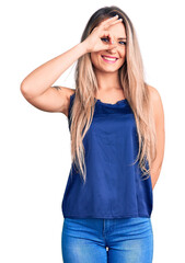 Canvas Print - Young beautiful blonde woman wearing casual sleeveless t-shirt smiling happy doing ok sign with hand on eye looking through fingers