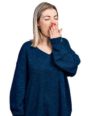 Young blonde woman wearing casual sweater bored yawning tired covering mouth with hand. restless and sleepiness.