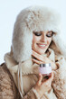 © Alliance - smiling stylish woman in winter coat and fur hat on white