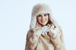 © Alliance - smiling modern woman in winter coat and fur hat on white