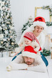 © Serenkonata - Happy family under Christmas tree. baby boy in Santa Claus hat with gifts under Christmas tree with many gift boxes presents. Happy Holidays, New year. Cozy warm winter evening at home. Xmas time