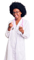 Poster - Young african american woman wearing doctor coat and stethoscope pointing fingers to camera with happy and funny face. good energy and vibes.