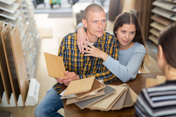 Wall Mural - Seller advises married couple in choosing a laminate in a hardware store