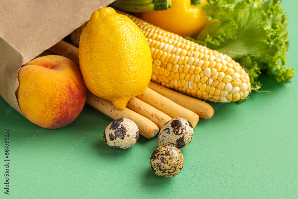 Paper shopping bag with fresh vegetables on green background