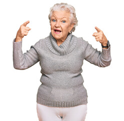 Wall Mural - Senior grey-haired woman wearing casual winter sweater smiling amazed and surprised and pointing up with fingers and raised arms.