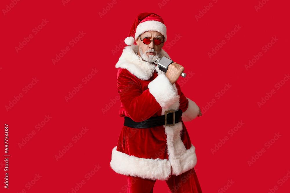 Santa Claus in sunglasses with microphone singing on red background