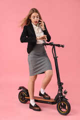 Poster - Portrait of panicked businesswoman talking by phone while riding kick scooter on pink background