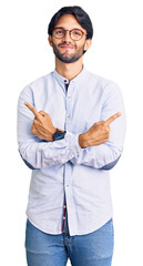 Poster - Handsome hispanic man wearing business shirt and glasses pointing to both sides with fingers, different direction disagree