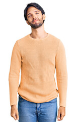 Poster - Handsome hispanic man wearing casual sweater relaxed with serious expression on face. simple and natural looking at the camera.