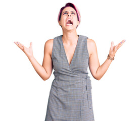 Canvas Print - Young beautiful woman with pink hair wearing casual clothes crazy and mad shouting and yelling with aggressive expression and arms raised. frustration concept.