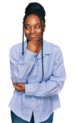 Sticker - Young african american woman wearing casual clothes with hand on chin thinking about question, pensive expression. smiling with thoughtful face. doubt concept.