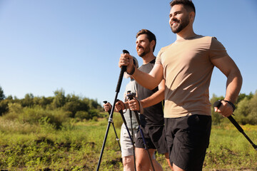 Poster - Happy men practicing Nordic walking with poles outdoors on sunny day